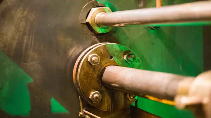 Close-up of steam engine components in the Engine Rooms at Tower Bridge. Brass-coloured machinery is illuminated in green.