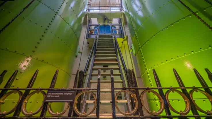 A floor-level view of Tower Bridge's Victorian steam accumulators. They are made from steel and painted a vibrant green.